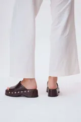 Sueco de cuero color marrón con plataforma y detalle de tachas plateadas.