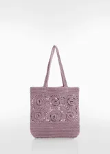 Bolso de mano tipo tote bag color lila, tejido a croché con diseño de flores en relieve.