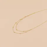 Gargantilla doble de oro amarillo 9k, con cadena fina y pequeñas esferas distribuidas a lo largo de la misma.