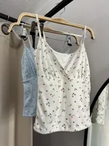 Musculosa blanca con estampado floral, escote en V y tirantes finos.
