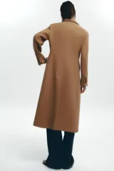 Abrigo largo color camel de Zara Woman Collection, confeccionado en hilatura con lana. Tiene cuello solapa con muescas, manga larga, falsos bolsillos delanteros, forro interior a contraste y cierre frontal con botones.