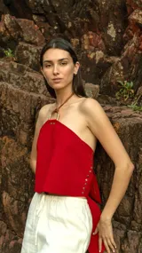 Top rojo de cuero pecarí con aplique de bronce en el cuello y espalda ajustable.