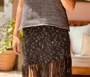 Falda negra tejida en lurex con flecos y detalles en crochet.