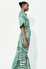 Vestido midi camisero con estampado de rayas verdes y blancas, cuello camisero, botonadura frontal, mangas cortas raglán, elástico en la cintura y cinturón extraíble para atar.