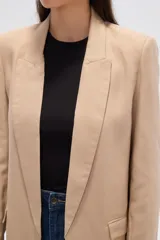 Blazer color beige, de corte holgado, con solapas anchas y bolsillos frontales.
