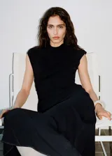 Vestido midi negro sin mangas, con cuello perkins, cintura drapeada y diseño evasé. Cierre de cremallera en la parte posterior y forro interior.