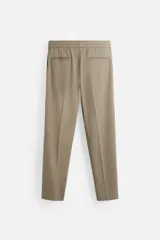 Pantalón color arena de corte recto, confeccionado en tejido elástico. Cuenta con cintura elástica ajustable con cordón, bolsillos laterales y bolsillos de vivo en la parte trasera.