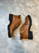 Borcegos de cuero color marrón con textura tipo reptil, caña baja, ajuste con dos correas con hebilla y suela track color negro.