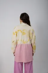 Buzo oversize color crema con estampado de hojas en tonos verde y amarillo, cuello alto con medio cierre metálico y jareta en la cintura para ajustar.