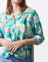 Blusa estampada de seda fría marca Figueroa & Flower. Tiene cuello a la base y escote en V, detalle de diferente estampa en hombros y espalda, apertura central con botones de nácar, mangas 3/4 regulables con presilla y botón, y terminación de ruedo con nudo.