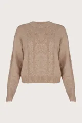 Suéter color taupe de cuello redondo, con ribete en los puños y tejido de cable al frente y a los costados. Tiene pequeñas lentejuelas integradas en el tejido.