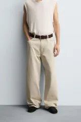 Pantalón de jean blanco, corte holgado y amplio en toda la pierna, tiro medio, tejido ligero, cinco bolsillos, efecto lavado y cierre frontal con cremallera y botón.