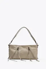 Bolso de hombro color gris con detalle de tiras y pasados metálicos en el cuerpo. Bolsillos con cremallera en la parte delantera. Asa de hombro. Bolsillo interior. Cierre mediante cremallera.