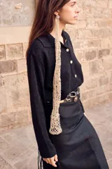 Cinturón negro de cuero con apliques de tachas plateadas y doradas con forma de soles, caballos y flores. Se ajusta con un lazo en la parte posterior.