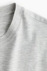 Remera gris de corte recto en punto suave de algodón, con cuello redondo ribeteado y hombros ligeramente caídos.