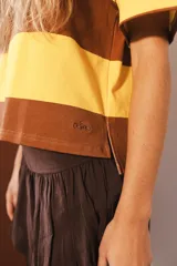 Remera de algodón a rayas horizontales marrones y amarillas, de corte cuadrado y mangas cortas.