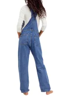 Jardinero de denim azul con silueta holgada, bolsillos delanteros, laterales y traseros, tirantes ajustables con enganche clásico y cierre lateral de botones.