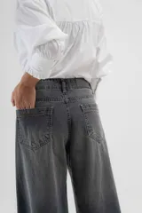 Pantalón de jean azul de pierna ancha y tiro medio, con cinco bolsillos y pespuntes a contratono.