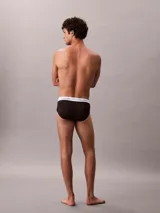 Pack de tres slips negros de algodón con cintura elástica blanca con el logo de Calvin Klein.
