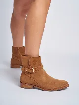 Bota corta de gamuza color marrón, con taco cuadrado y punta fina. Presenta una correa con hebilla dorada alrededor del tobillo y cierre lateral.