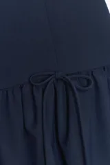 Vestido corto azul marino sin mangas, con cuello redondo, falda fruncida con lazos decorativos y cierre trasero con cremallera oculta.