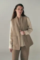 Chaleco color beige, entallado, con solapa, bolsillos plaqué y terminaciones envivadas.