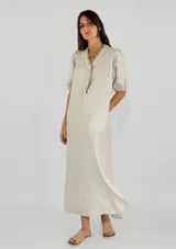 Vestido largo color beige, con escote en V, mangas 3/4 abullonadas y botones frontales.