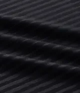 Remera deportiva de manga corta y cuello redondo, color beige claro, con textura acanalada vertical. Presenta detalles reflectantes en los hombros.