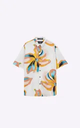 Camisa de manga corta con estampado floral en tonos amarillos, naranjas, azules y marrones sobre fondo blanco. Calce oversize y canesú en la espalda.