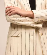 Blazer oversized color crudo con rayas verticales negras, cuello solapa, mangas largas, cierre con un botón y bolsillos simulados.