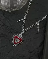 Gargantilla plateada con cadena de eslabones, dije central de corazón rojo con ojo y rosa, y dos dijes de dagas a los lados.