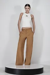 Pantalón de vestir color marrón claro, de tiro alto y corte palazzo. Presenta una cintura con cordón trenzado.
