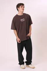 Remera de manga corta color marrón oscuro con efecto gastado, corte oversize y cuello redondo. Presenta un pequeño estampado frontal con texto en blanco y rosado que dice "SPAGHETTI WESTERN" y "Director's Club".