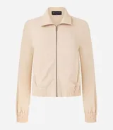 Campera bomber color beige, confeccionada en tejido airflow, con cuello solapa, cierre frontal con cremallera, mangas largas y puños/bajo elásticos.