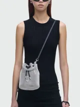 Bolso bombonera pequeño Marc Jacobs modelo The Mini Bucket, con cuerpo plateado brillante, asa corta trenzada, correa larga de cuero y logo metálico en el frente.