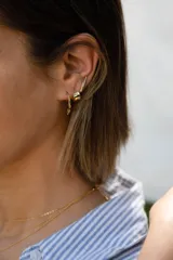 Aros dorados tipo argolla con incrustaciones de circonitas verdes y dije colgante de circonita verde en forma de lágrima.