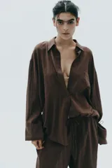 Camisa marrón de algodón, corte amplio, con cuello solapa, manga larga con puños, bolsillo de parche en el pecho, pinzas en la espalda y cierre frontal con botones.