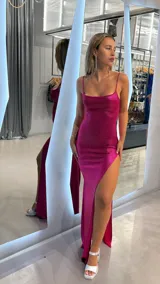 Vestido largo fucsia con breteles finos y abertura lateral en la pierna.