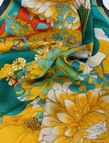 Pañuelo cuadrado de satén estampado con diseño floral en tonos naranja, celeste y lila.