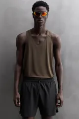 Pantalón corto deportivo color marrón oliva, con cintura elástica ajustable con cordón, bolsillos frontales y bolsillo trasero con cierre. Presenta forro interior y detalle de logo estampado en la pernera.