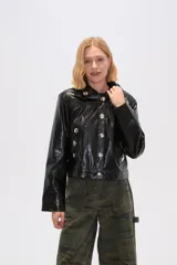 Chaqueta corta marrón de cuero sintético con cuello camisero, cierre frontal con botones metálicos y bolsillos tipo parche con botón.