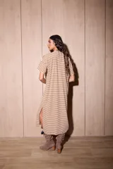 Vestido largo de algodón, color blanco hueso, con rayas horizontales marrones. Presenta cuello redondo, mangas cortas y corte recto.