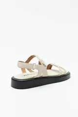 Sandalias color beige con plataforma negra, tiras trenzadas y ajuste con velcro en el talón.
