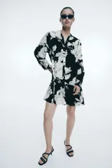 Vestido corto de viscosa con estampado floral en blanco y negro. Modelo de corte holgado con cuello mao, botones delanteros y mangas globo largas con abertura y botón en los puños. Costura fruncida en la pollera para un efecto evasé.