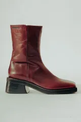 Bota corta de cuero color bordó con acabado natural, caña ajustada y punta suavemente afinada. Posee un taco ancho y estable de aproximadamente 5 cm.