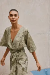 Vestido midi color verde oliva con estampado floral, escote en V, manga corta amplia y detalle drapeado en la cintura.