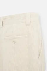 Pantalón largo color beige confeccionado en pana de algodón, de corte wide fit, con bolsillos frontales y traseros.