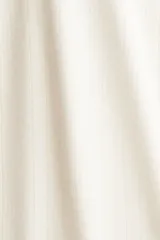 Pantalón de pijama color blanco roto, confeccionado en tejido pointelle suave. Presenta piernas levemente acampanadas, elástico revestido en la cintura con cordón fino para ajustar y ribete de volados.