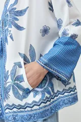 Kimono blanco con estampado floral azul, con mangas 3/4 y cierre frontal con cordón.