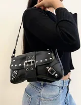 Cartera negra con correa corta para el hombro, con apliques de tachas y hebillas plateadas.